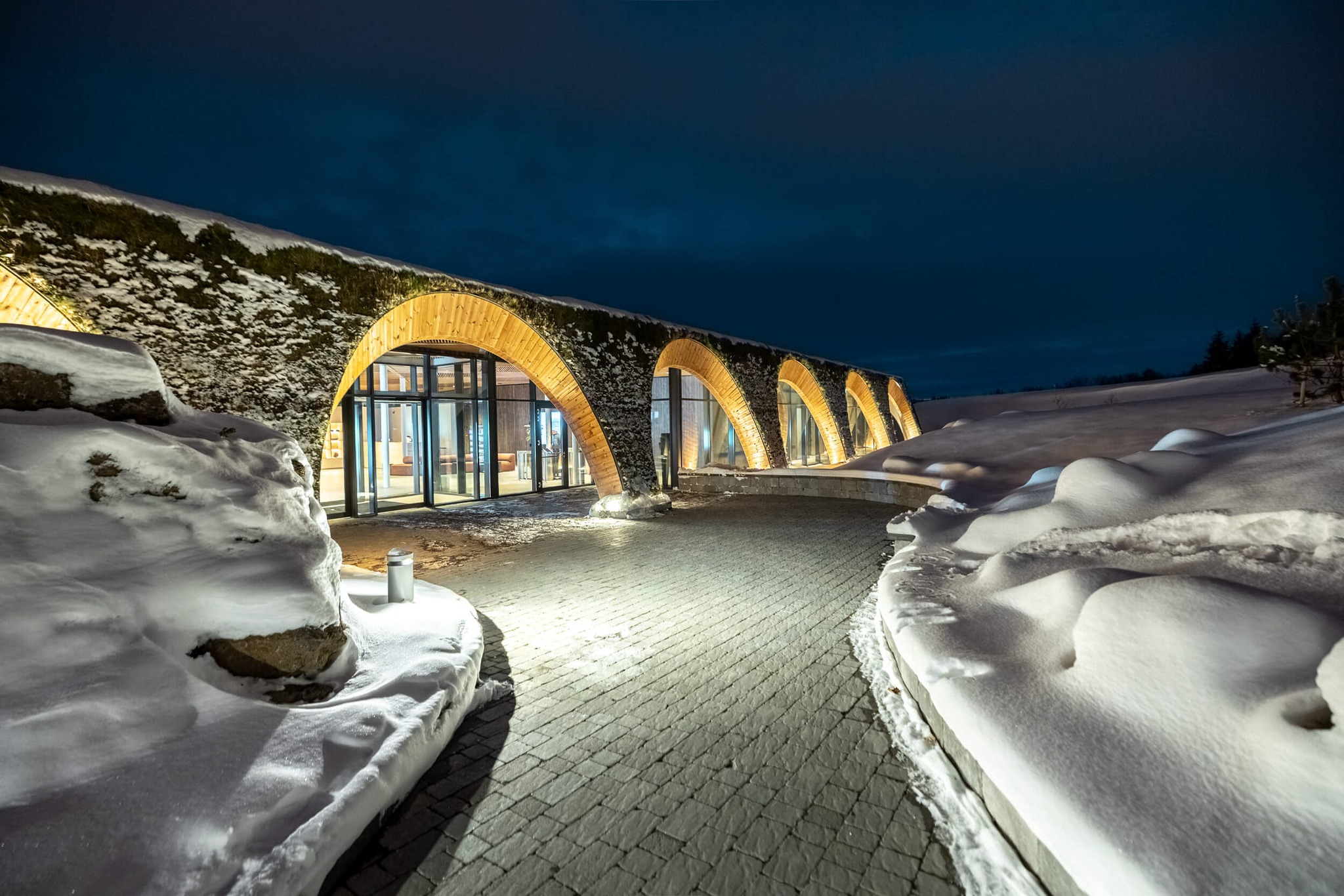 Upplýst bogabygging með torfþaki að vetrarkvöldi